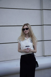 a lady wears a white knitted polo shirt with black midi skirt